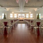 Liberty Hall set up for a wedding ceremony for Christmas. There are Christmas trees on each side of the room.